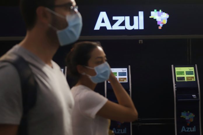 Passageiros com máscaras de proteção caminham em frente a guichês da Azul no aeroporto de Congonhas, em São Paulo